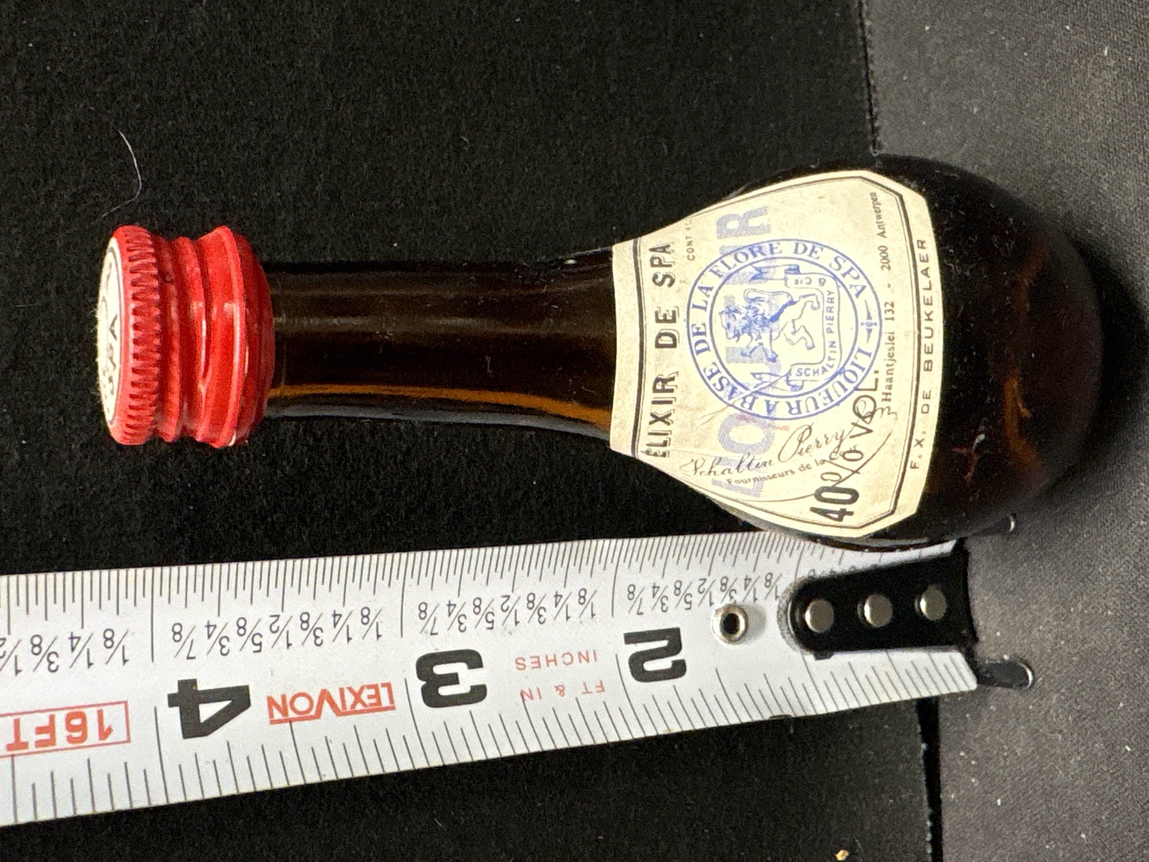 LOT 2026-542 — Petite bouteille de collection en verre ambré, avec bouchon rouge texturé et… — photo 1