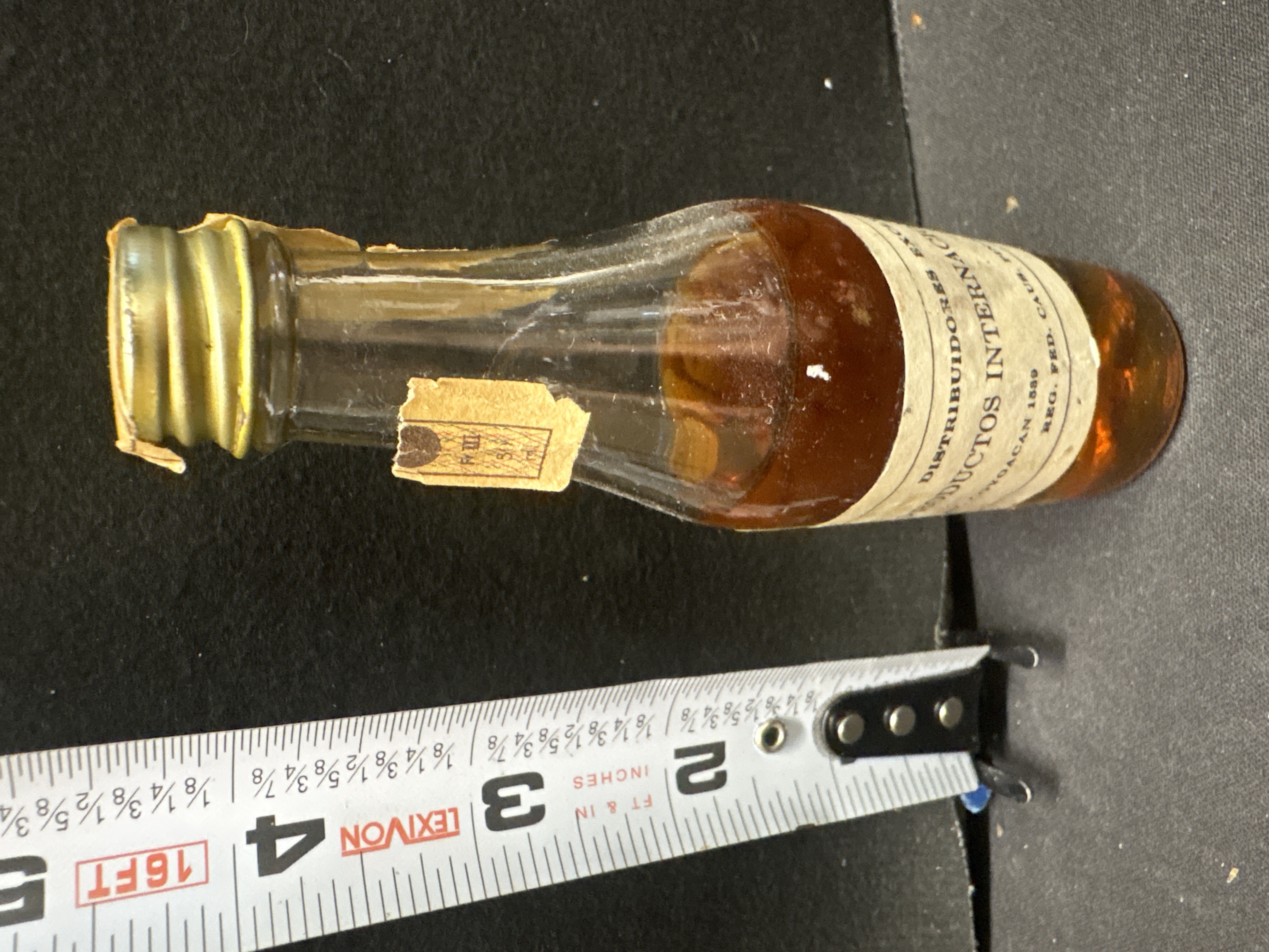 LOT 2026-558 — Petite bouteille en verre au contenu ambré, scellée et jamais ouverte selon… — photo 2